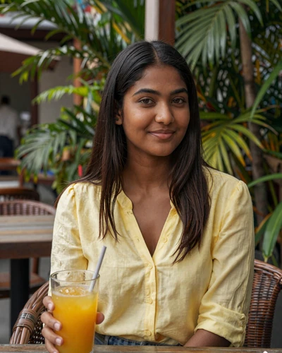 Beautiful Indo-Guyanese woman enjoying a tropical drink at a Georgetown outdoor café