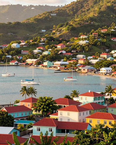 Colorful St. George's harbor in Grenada with pastel buildings climbing green hillsides above turquoise Caribbean water